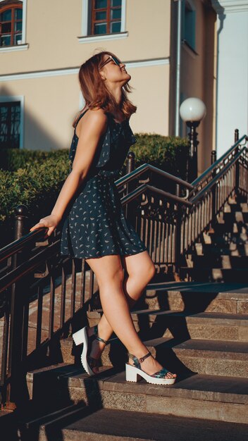 Mujer atractiva en vestido camina por las calles de la ciudad vieja en un día soleado. Foto vertical