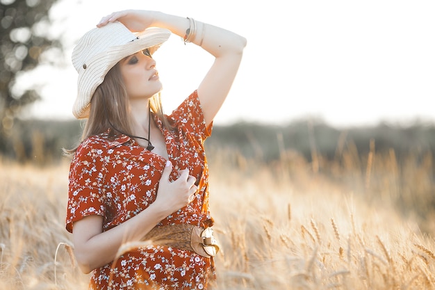 Mujer atractiva con un vestido rojo en el campo de trigo