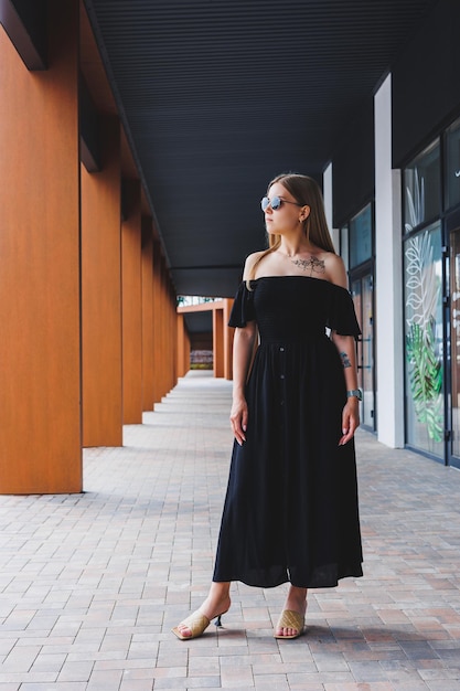 Mujer atractiva en un vestido de verano negro y sandalias de tacón Moda casual de mujer de verano