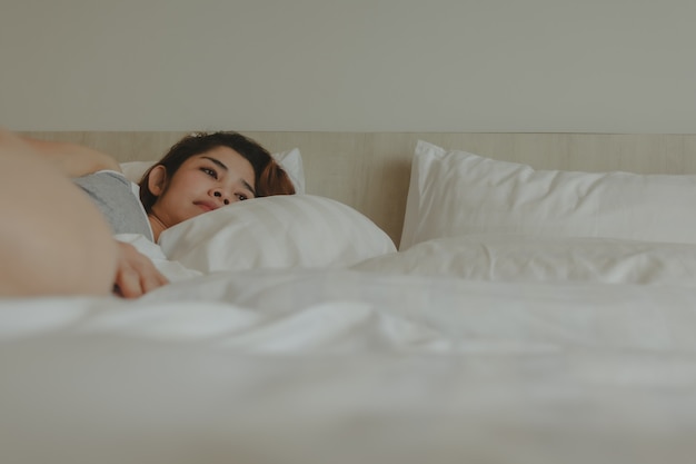 Mujer atractiva yacía en la cama sintiéndose relajada y acogedora por la mañana