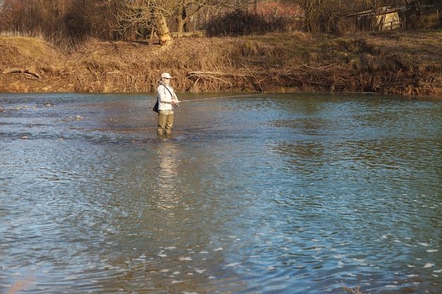 Mujer atrapa peces girando de pie en un río