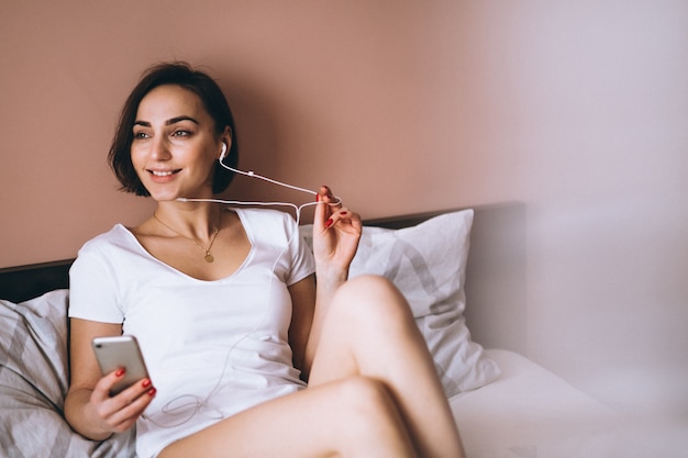 Mujer con auriculares en la cama