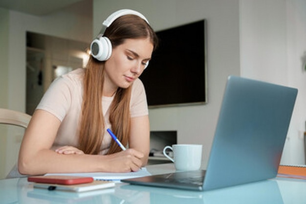 una mujer con auriculares y una computadora portátil en su escritorio