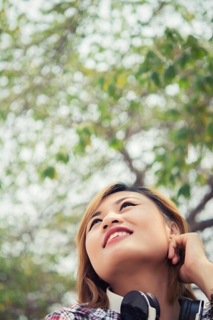 Foto mujer con auriculares contra los árboles