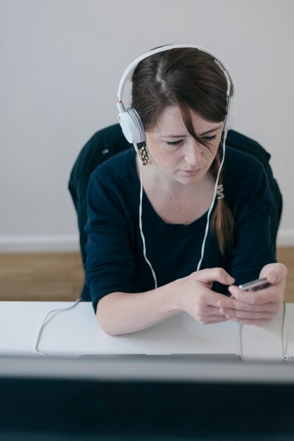 Foto mujer con auriculares enviando mensajes de texto en su teléfono móvil