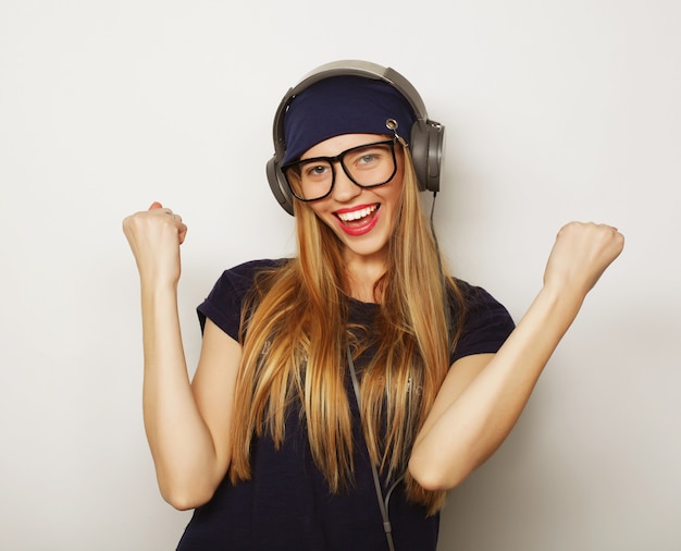 Mujer con auriculares escuchando música. Chica adolescente de música bailando contra blanco.