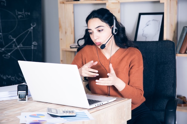 Mujer en auriculares estudiar online en portátil tomar notas