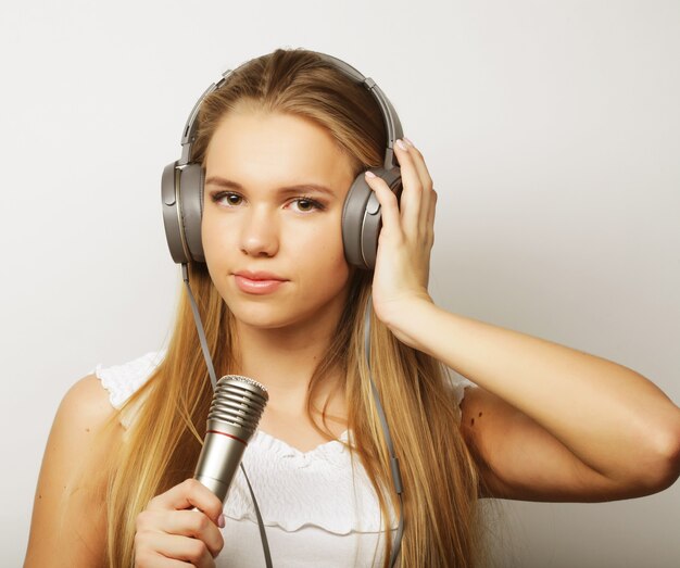 Mujer con auriculares y micrófonos escuchando música y cantando