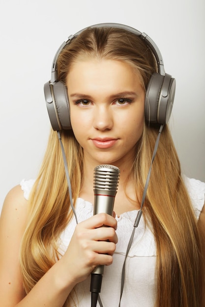 Mujer con auriculares y micrófonos escuchando música y cantando