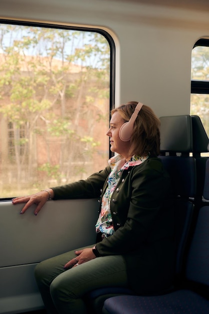 Mujer con auriculares mira por la ventana en un tren