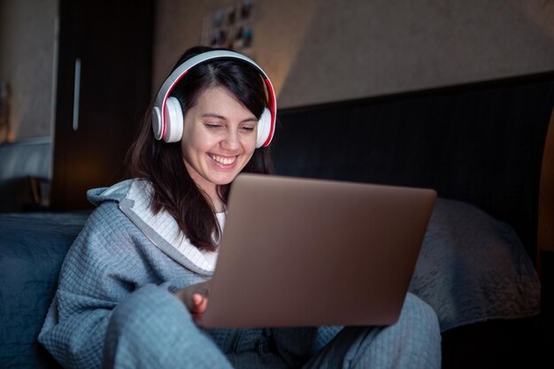 La mujer con auriculares que trabaja en una computadora portátil tiene un trabajo remoto de videollamada desde casa