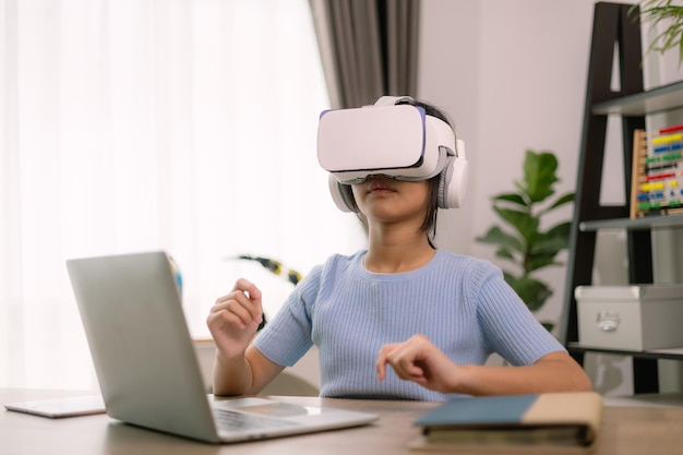 Foto una mujer con auriculares de realidad virtual está sentada en un escritorio con una computadora portátil