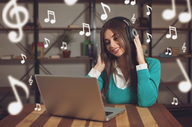 Foto mujer con auriculares está sentada en la mesa de madera