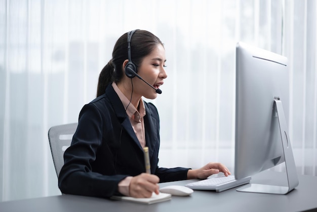 Una mujer con auriculares se sienta en un escritorio con una computadora y un monitor que dice centro de llamadas.