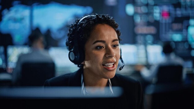Una mujer con auriculares se sienta frente a la pantalla de una computadora.