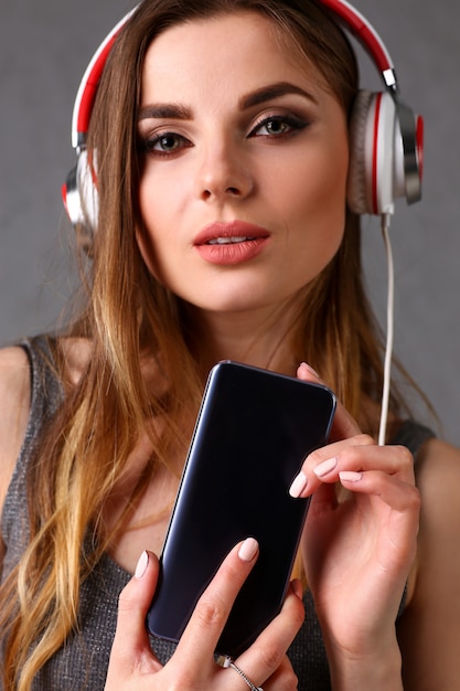 Mujer en auriculares con smartphone en la mano.