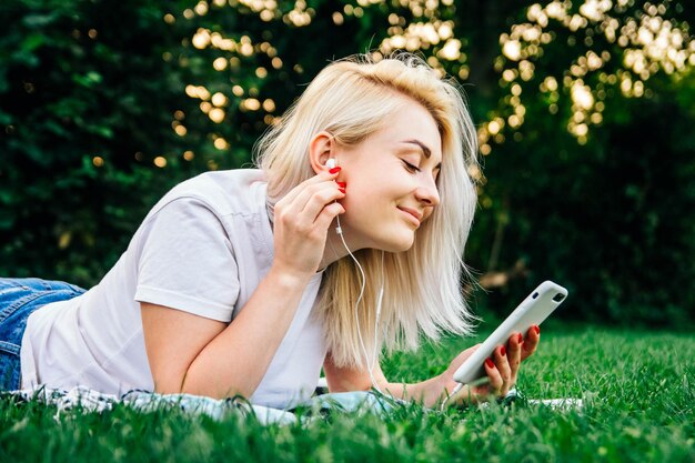 Mujer en auriculares y smartphone en manos escucha música sobre fondo verde