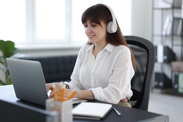 Mujer con auriculares viendo un webinar en la mesa de la oficina