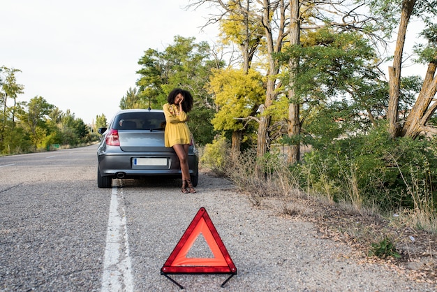 Mujer con auto roto y triángulo