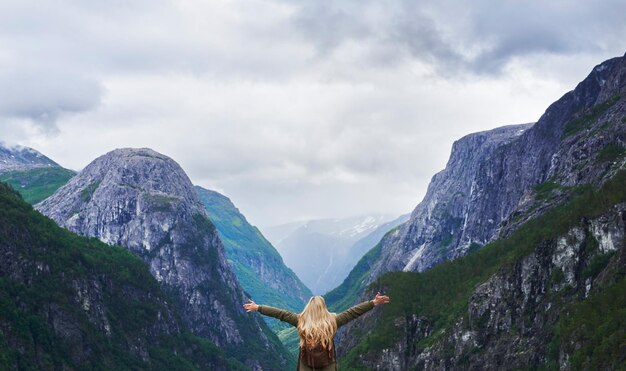 La mujer de aventuras de viaje celebra los brazos levantados a la vista del majestuoso valle glacial en la exploración descubre la hermosa tierra