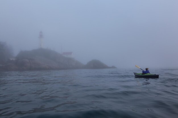 Mujer aventurera es kayak de mar cerca de un faro