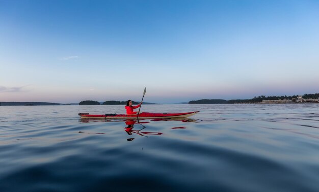 Mujer aventurera en kayak de mar remando en el océano pacífico