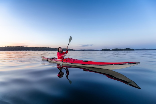 Mujer aventurera en kayak de mar remando en el océano pacífico