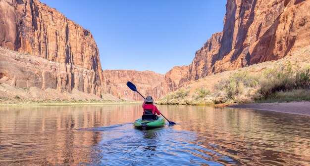 Mujer aventurera en un kayak remando en el río colorado glen canyon arizona