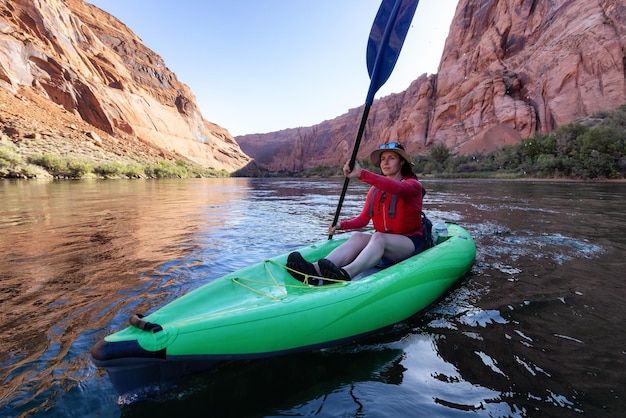 Mujer aventurera en un kayak remando en el río colorado