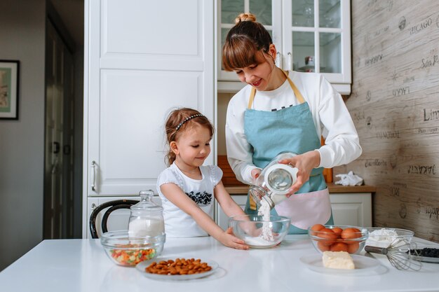 Una mujer ayuda a su madre a preparar un pastel en la cocina.