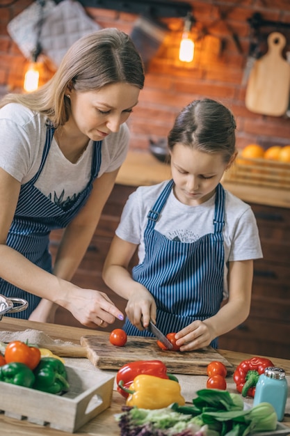 Mujer ayudando a hija con tomates