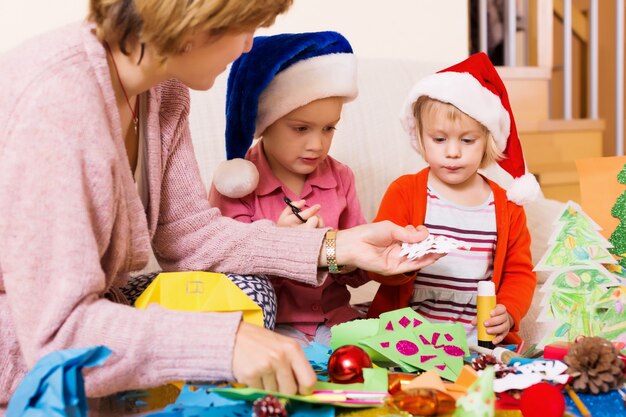 mujer ayudando a las niñas a hacer la decoración de Navidad