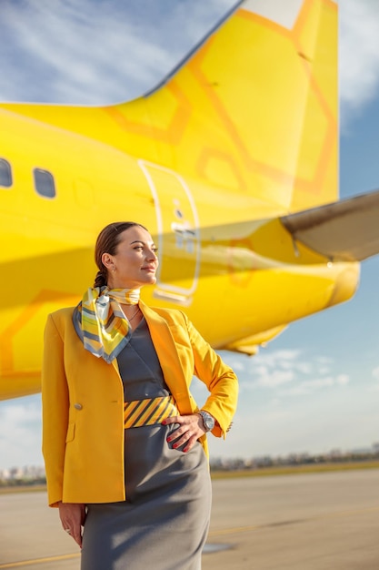 Mujer azafata con uniforme de azafata de aviación mientras está de pie al aire libre en el aeropuerto