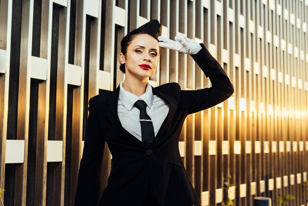 Foto mujer azafata en uniforme posando sobre fondo de edificio