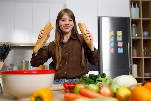 Mujer con una baguette rota en las manos en la cocina