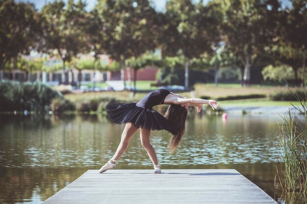 Foto mujer bailando ballet en el muelle sobre el lago