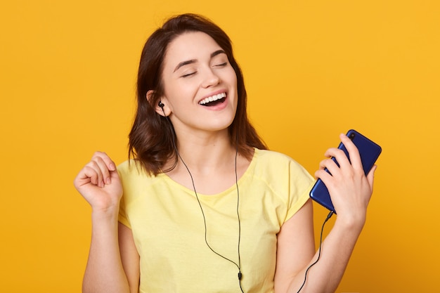 Mujer bailando y escuchando música en auriculares desde un teléfono inteligente o reproductor de mp3