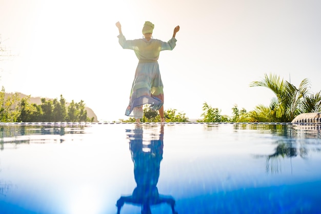 Mujer bailando con vestido junto a una piscina