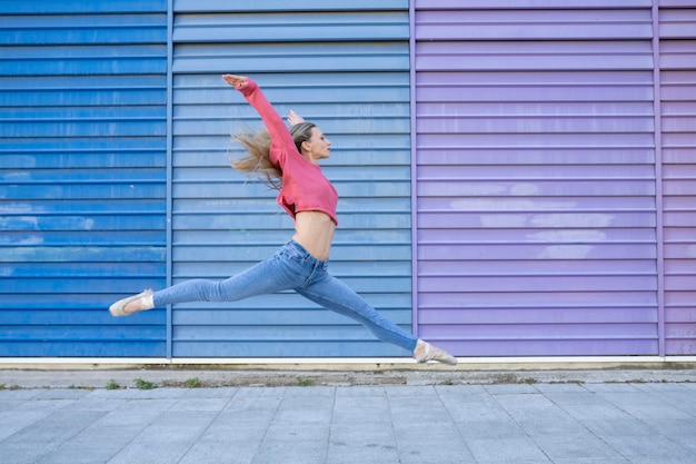 Mujer bailarina saltando delante de una pared colorida