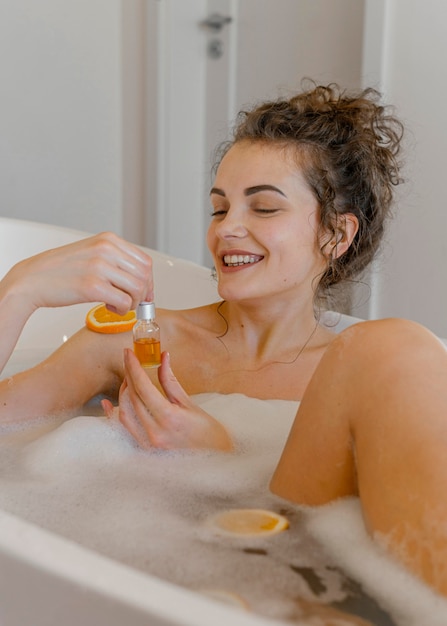 Mujer bañándose con rodajas de naranja en el baño