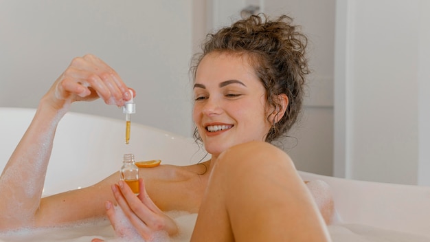 Foto mujer bañándose con rodajas de naranja en el baño