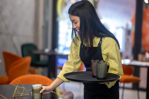 Foto mujer, con, bandeja, poniendo, vidrio, en la mesa