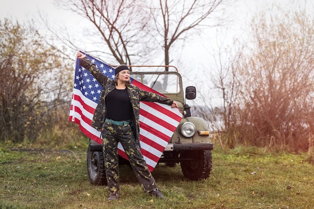 Foto mujer con bandera americana y coche militar