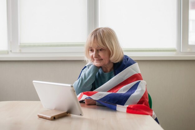 Mujer con bandera británica ve la transmisión de las celebraciones del Jubileo de Platino de la Reina en línea en su casa