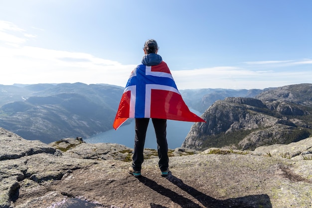Mujer con una bandera ondeante de Noruega en el fondo de la naturaleza