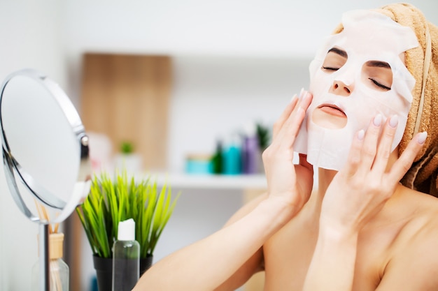 Foto mujer en el baño aplica cosméticos al cuidado de la piel