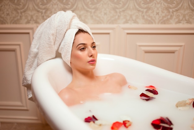 Mujer en el baño con pétalos de rosa