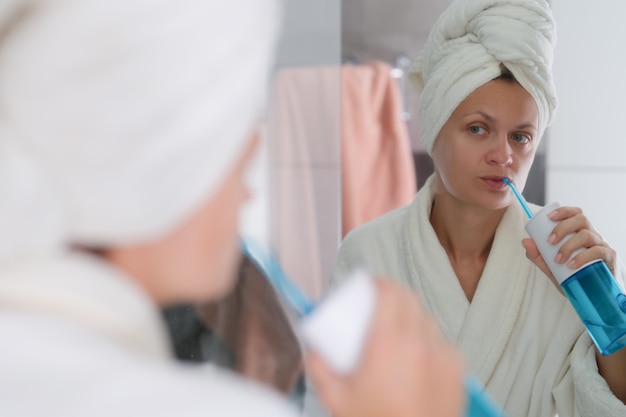 Mujer en el baño realiza limpieza higiénica de dientes