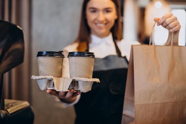 Mujer barista en la cafetería preparando café en vasos de cartón