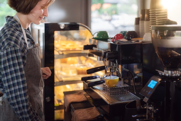 Mujer barista con delantal preparando café con cafetera en una cafetería